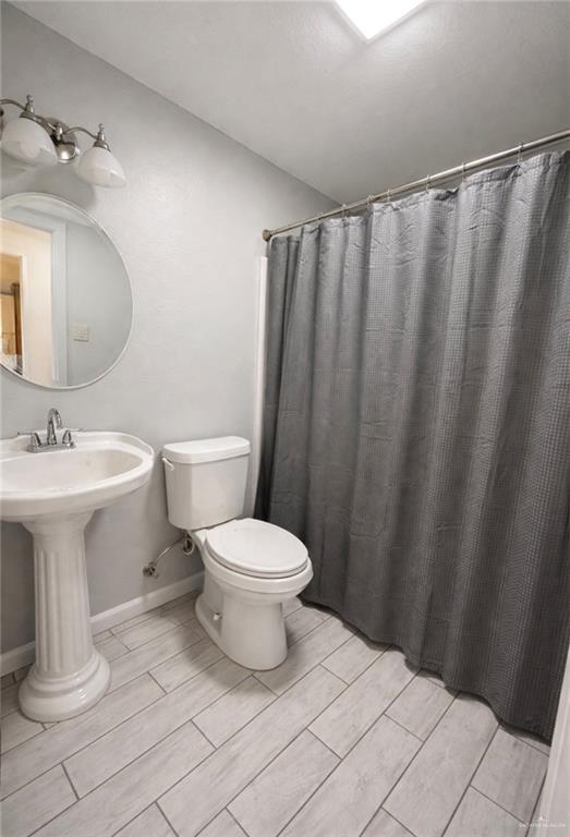 1403 North Shary Road Mission, TX 78572 - Photo 8 of 9 Full bath featuring a shower with shower curtain and wood finish floors