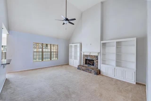 a view of an empty room with fireplace and a window