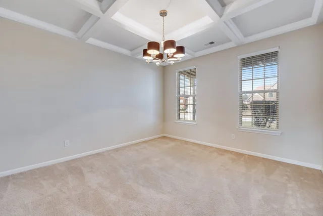 an empty room with windows and chandelier fan