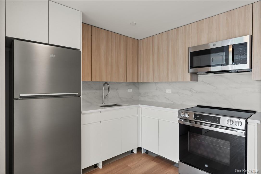 10 Lyon Place, Unit 3J White Plains, NY 10601 - Photo 6 of 17 a kitchen with stainless steel appliances white cabinets and a wooden floor