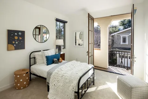 a bedroom with a bed a mirror on the wall and a large window