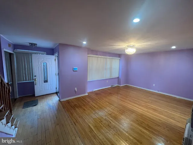 a view of an empty room with wooden floor and stairs