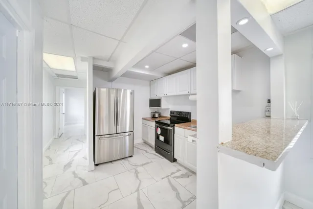 a kitchen with granite countertop a refrigerator and a stove top oven