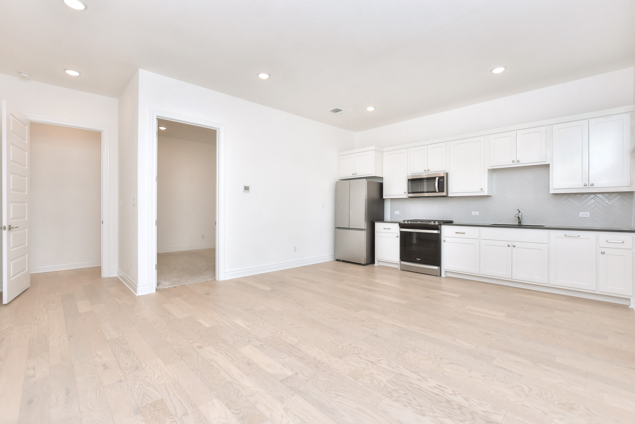 309 Wolf Rdg Road Georgetown, TX 78628 - Photo 22 of 39 Kitchen featuring stainless steel appliances, white cabinetry, light wood-type flooring, dark countertops, and recessed lighting