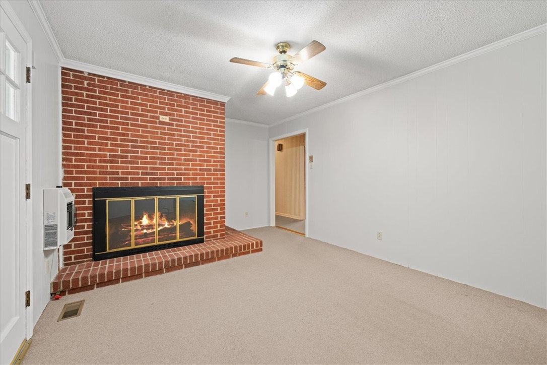 304 Shaw Road Honea Path, SC 29654 - Photo 9 of 39 This living room features a cozy fireplace with a brick surround.