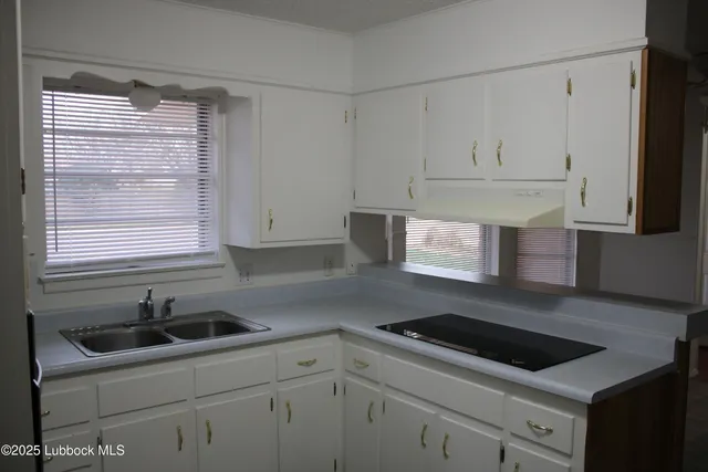 a kitchen with white cabinets appliances a sink and a window