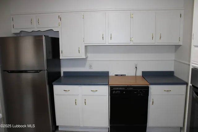 a kitchen with stainless steel appliances granite countertop a refrigerator a stove and a refrigerator with white cabinets