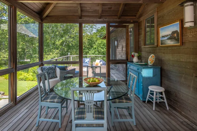 a view of a patio with couches chairs potted plants with wooden floor and fence