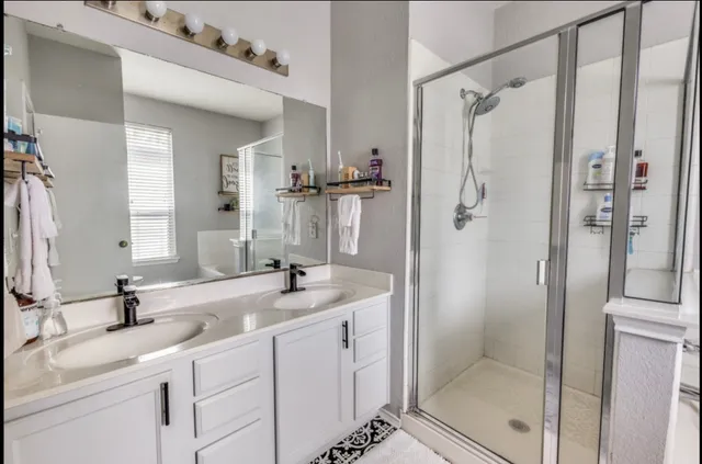 a bathroom with a double vanity sink mirror and shower