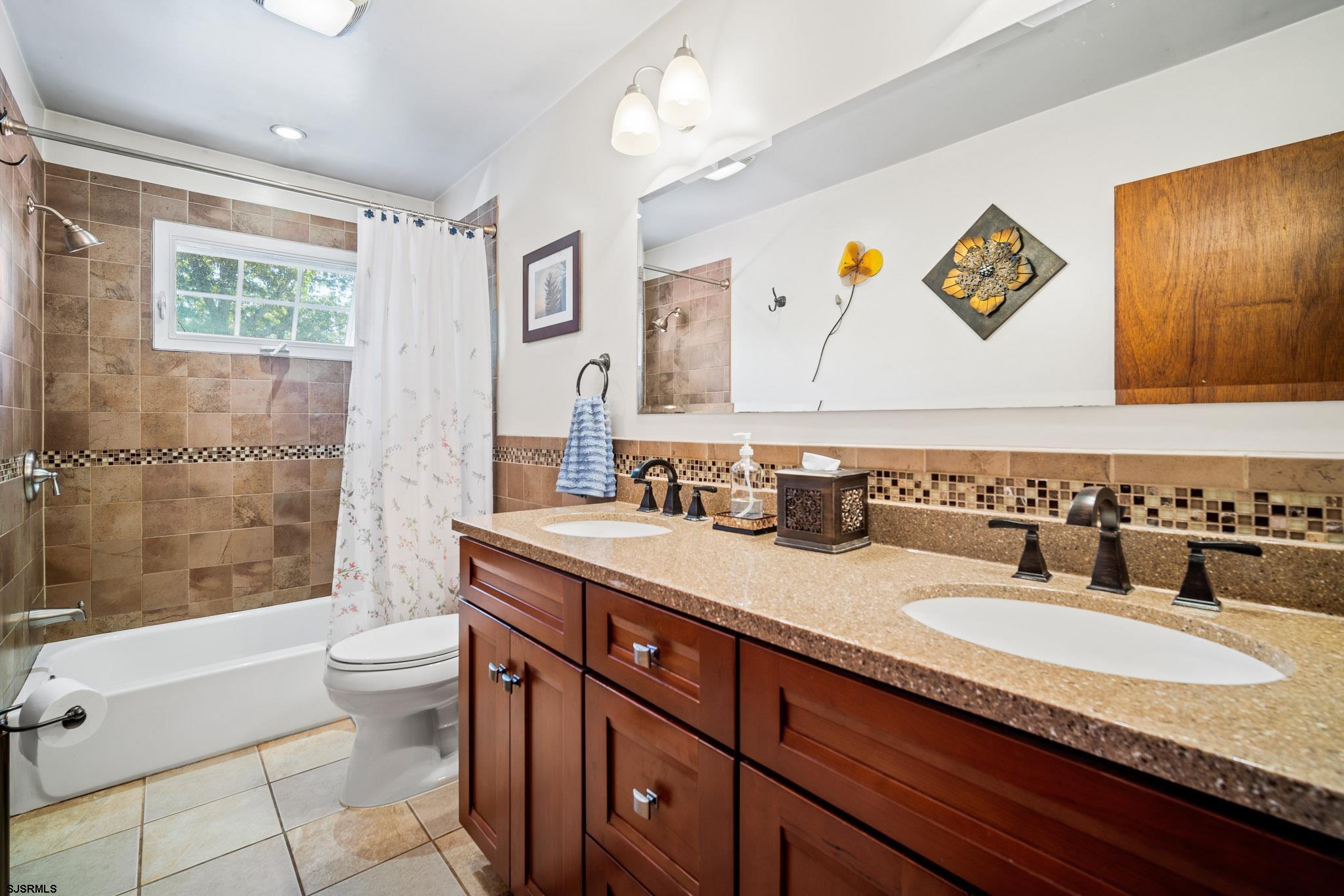 1326 Elwood Road Hammonton, NJ 08037 - Photo 23 of 36 a bathroom with a granite countertop sink a toilet a mirror a vanity a bathtub and shower