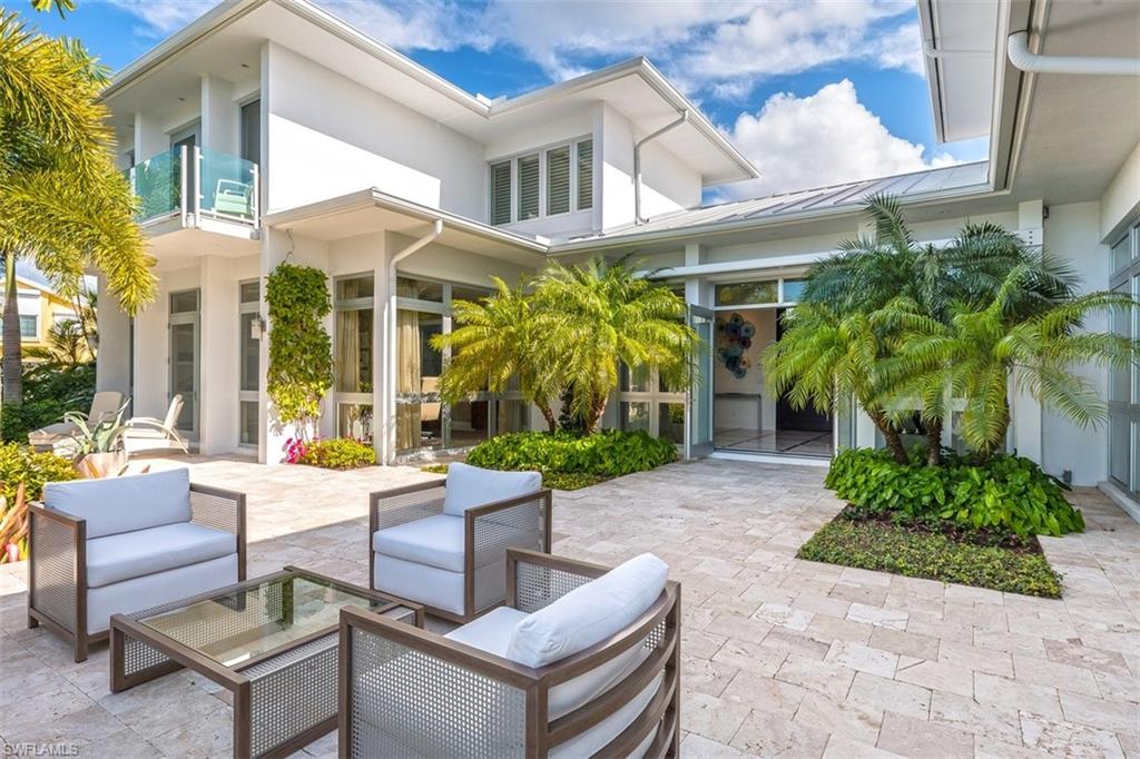 2290 Tarpon Road Naples, FL 34102 - Photo 28 of 35 a view of a patio with couches table and chairs potted plants and floor to ceiling window