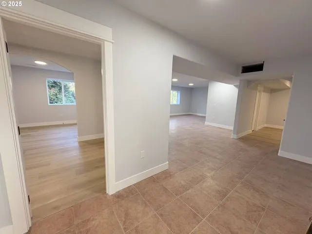 an empty room with wooden floor and bathroom view