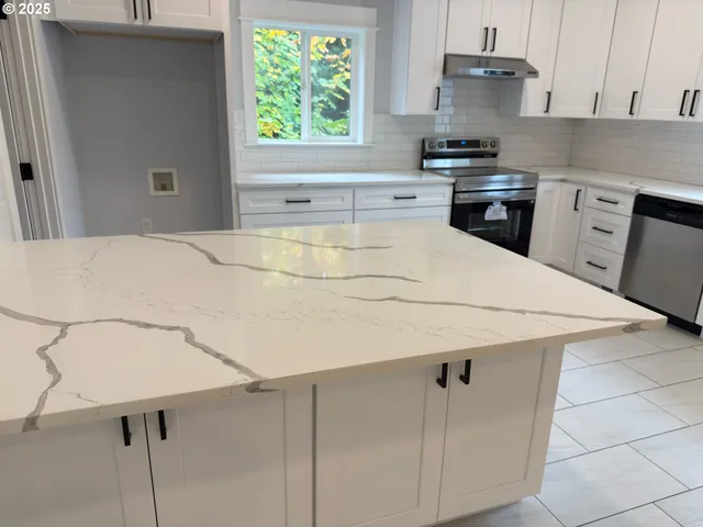 a kitchen with a white cabinets appliances and a window