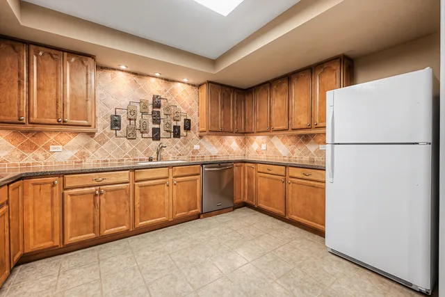 a kitchen with granite countertop a refrigerator a sink and white cabinets