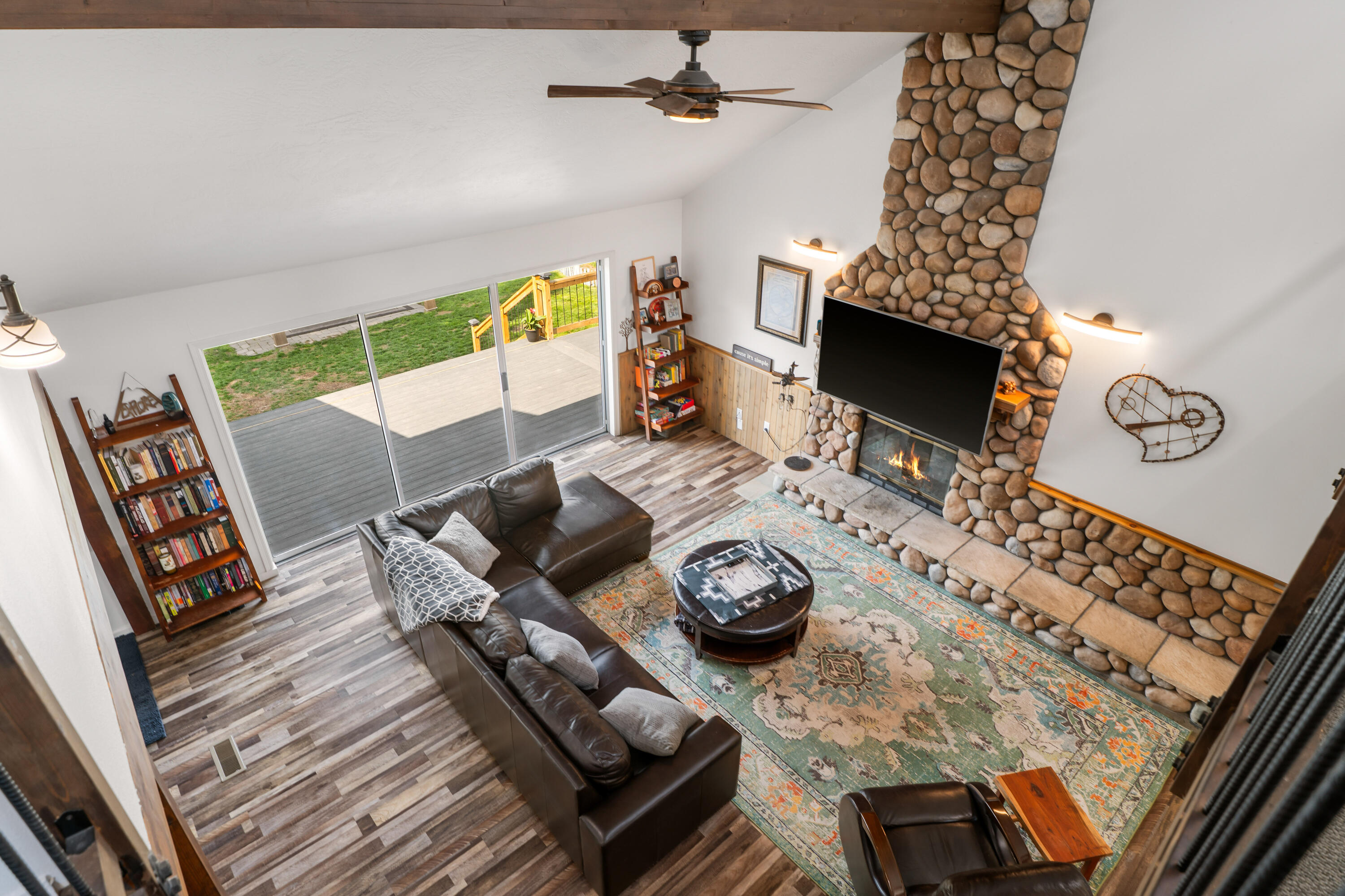 17062 Milky Way Bend, OR 97707 - Photo 7 of 39 Living room reveal from the loft with vaulted ceilings and floor-to-ceiling river-rock fireplace