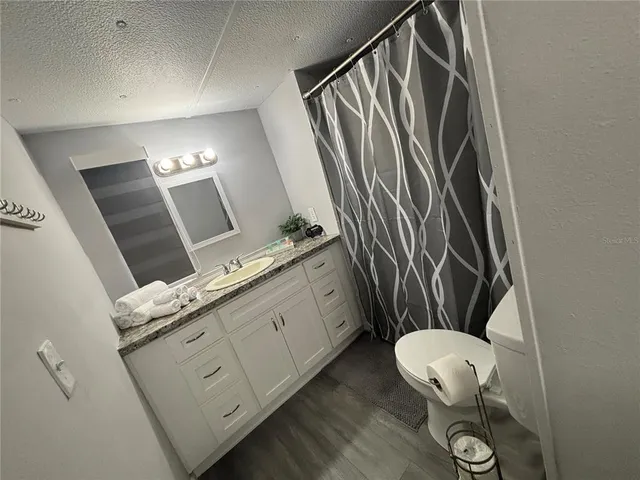 a bathroom with a granite countertop sink mirror vanity and toilet