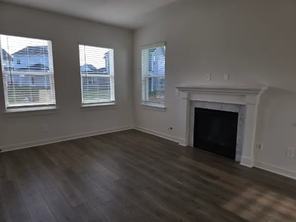 an empty room with wooden floor cabinet and windows