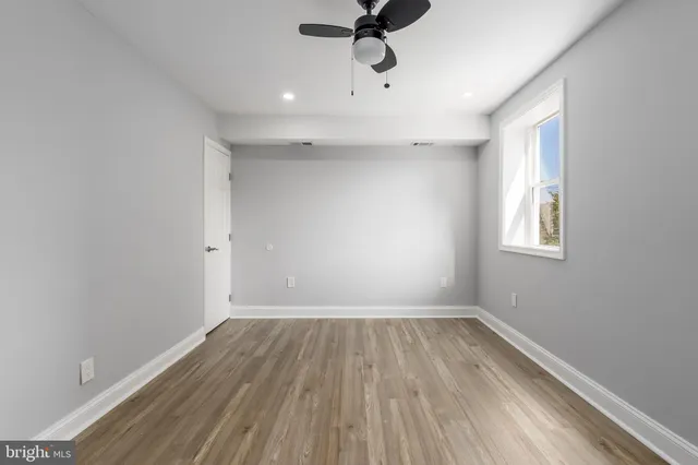 a view of an empty room with a window and wooden floor