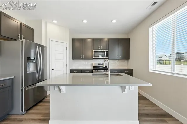 a kitchen with stainless steel appliances granite countertop a refrigerator a sink dishwasher a stove with wooden floors