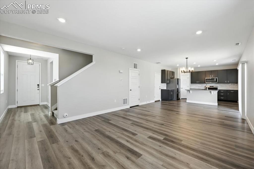 9891 Hidden Ranch Court Peyton, CO 80831 - Photo 9 of 44 an empty room with wooden floor kitchen view and a window