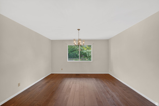 3120 North Apache Way Provo, UT 84604 - Photo 26 of 58 Spacious room featuring rich wood-finish flooring, a contemporary window, white baseboards, light neutral wall tones, and a bronze-finish chandelier