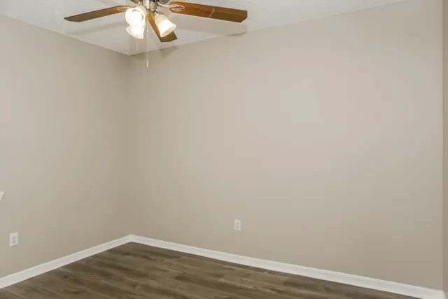 an empty room with wooden floor and fan