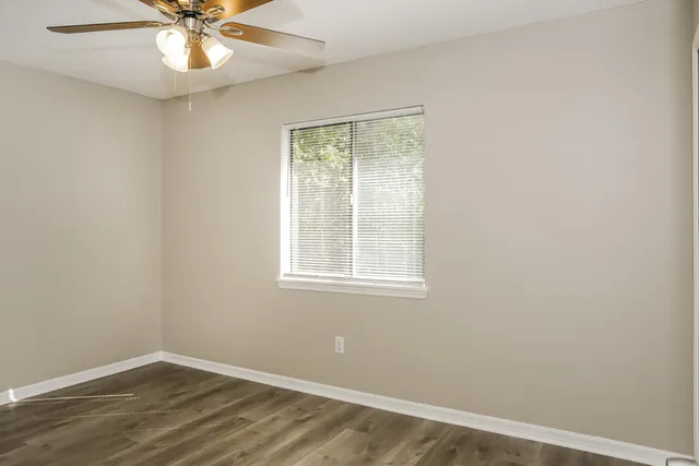 an empty room with a window and a fan