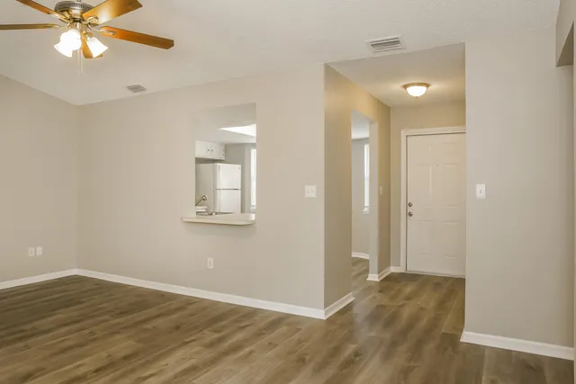 an empty room with wooden floor and a ceiling fan