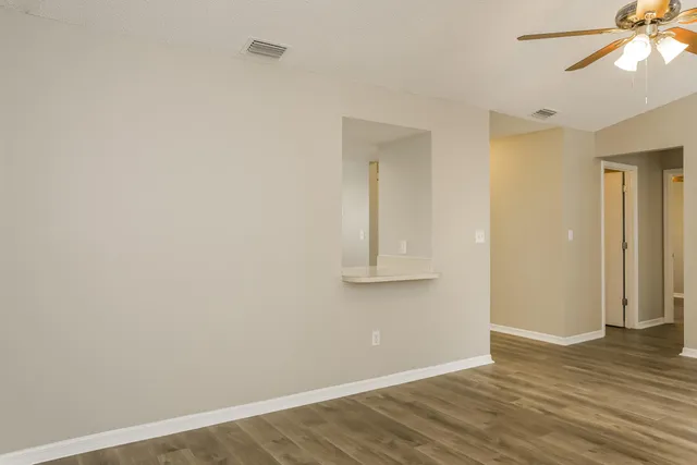 a view of empty room with wooden floor and fan
