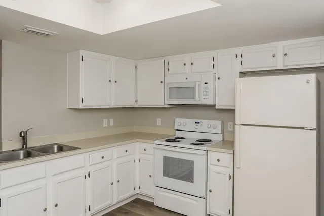 a kitchen with granite countertop white cabinets and white appliances