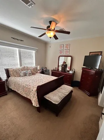 a bedroom with a bed a dresser and a chandelier