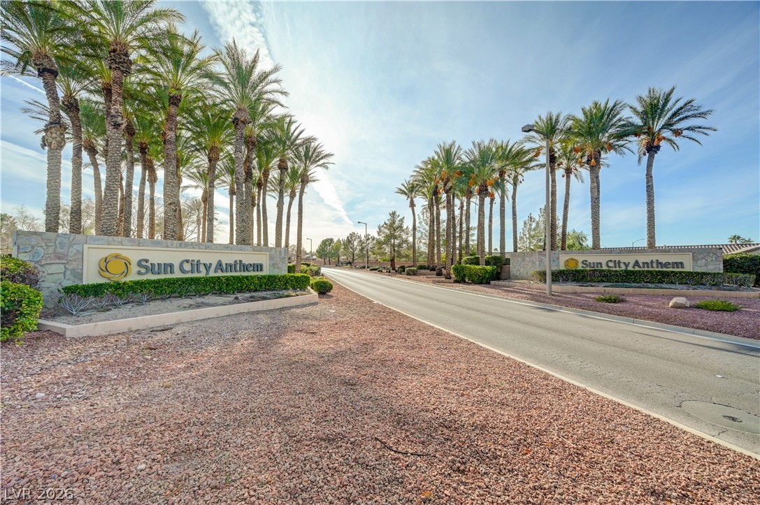 2529 Springville Way Henderson, NV 89052 - Photo 61 of 70 Towering palm trees frame the stone monument walls flanking the entrance roadway under sunny skies.
