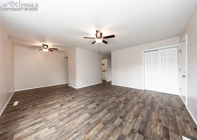a view of empty room with wooden floor and fan