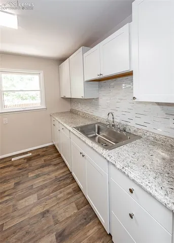 a kitchen with granite countertop wooden cabinets a sink and dishwasher