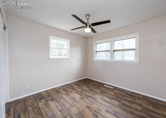 a view of empty room with wooden floor and fan