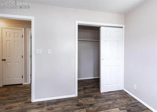 an empty room with wooden floor & closet area