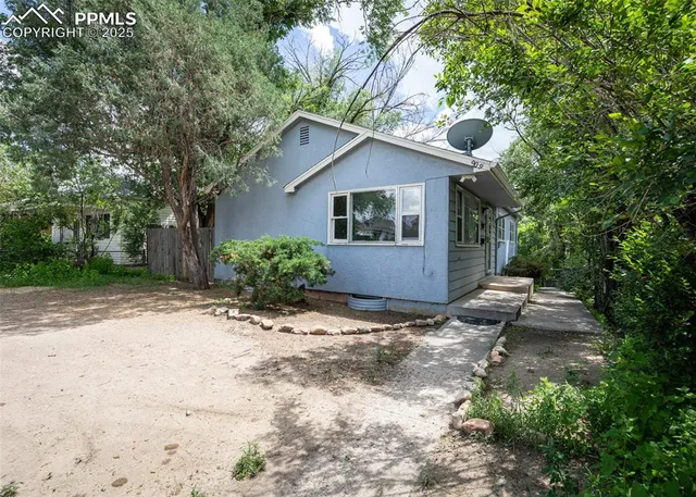 a view of a house with a yard and large trees