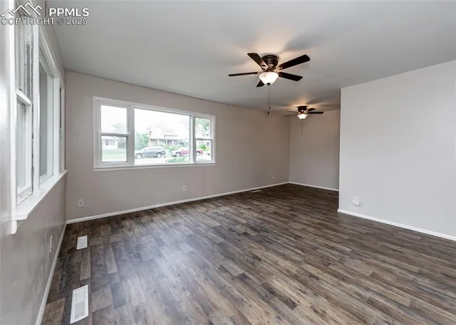 a view of an empty room with wooden floor and a window
