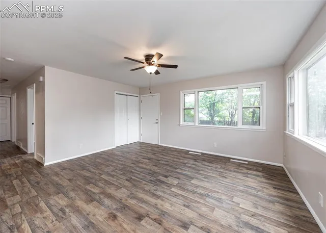 a view of empty room with wooden floor and fan
