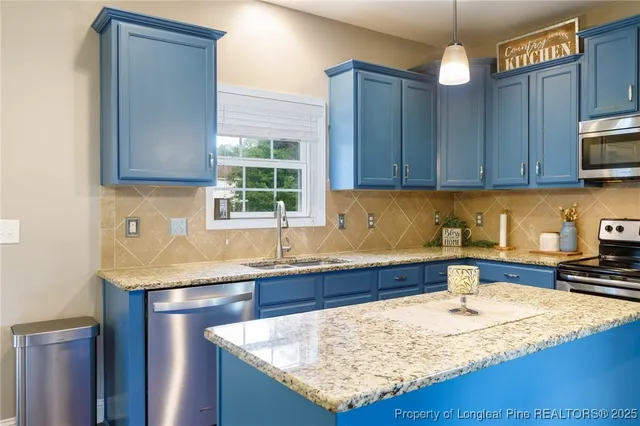 a kitchen with kitchen island granite countertop a sink a counter top space and cabinets