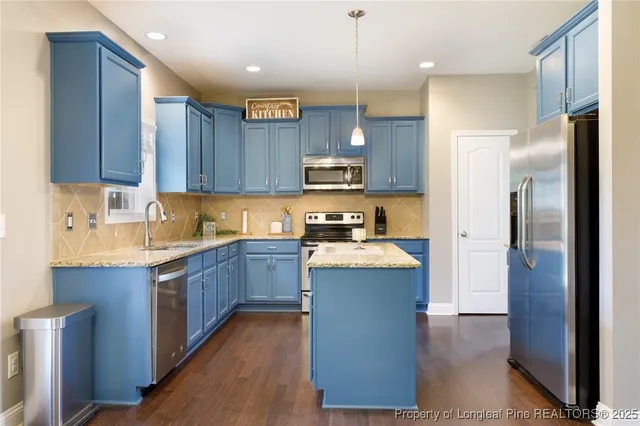 a kitchen with stainless steel appliances granite countertop a refrigerator a sink dishwasher a stove and a oven with wooden floor