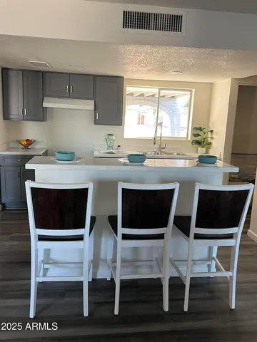 a kitchen with granite countertop a dining table chairs and a wooden floor