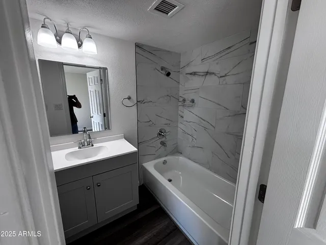 a bathroom with a tub sink a mirror a vanity and a shower
