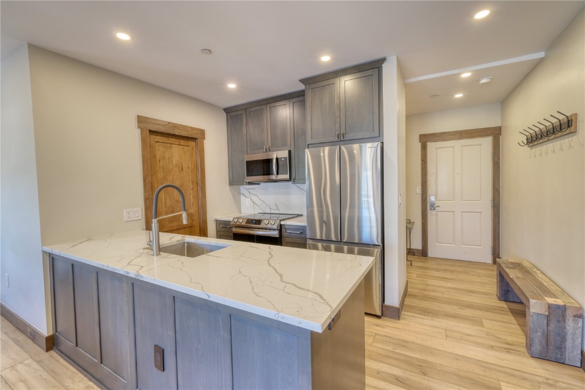 195 River Run Road, Unit 8013 Keystone, CO 80435 - Photo 3 of 38 Kitchen featuring tasteful backsplash, lvp flooring, quartz counters, stainless steel appliances