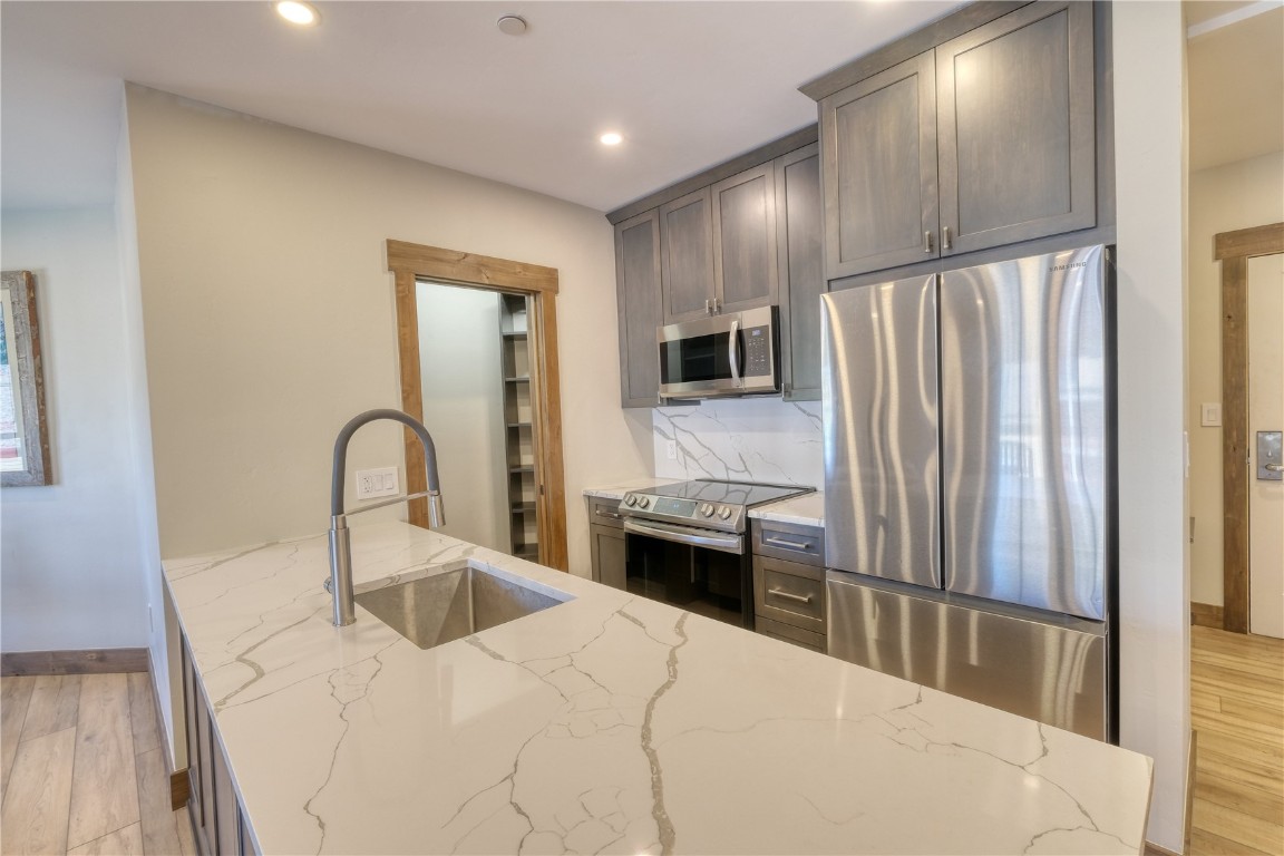 195 River Run Road, Unit 8013 Keystone, CO 80435 - Photo 4 of 38 Kitchen featuring tasteful backsplash, lvp flooring, quartz counters, stainless steel appliances