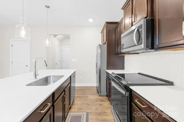 a kitchen with stainless steel appliances granite countertop a sink and dishwasher a stove top oven with wooden floor
