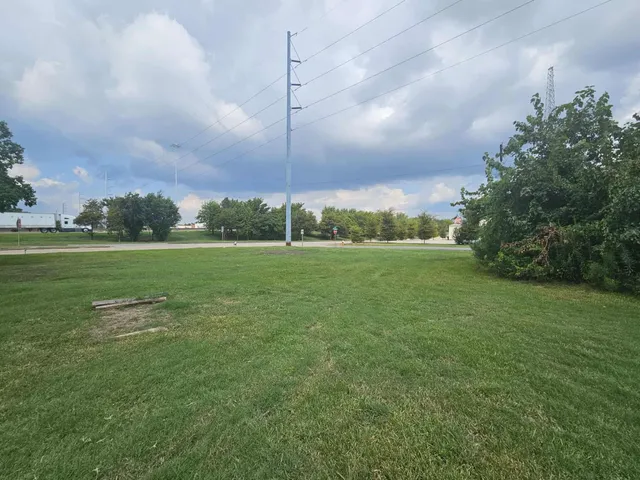 a view of a building with a big yard and large trees