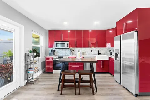 a kitchen with stainless steel appliances kitchen island granite countertop a dining table chairs refrigerator and sink