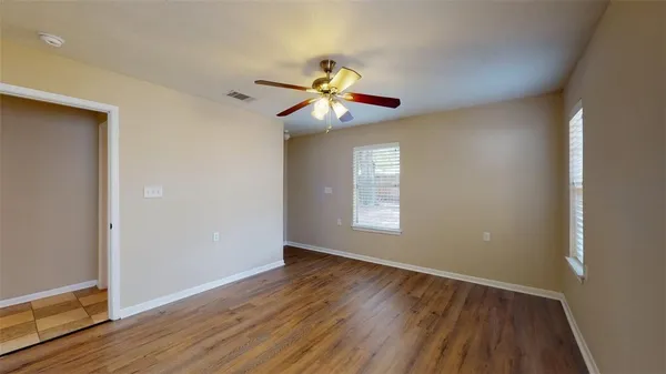 a view of an empty room with window and wooden floor