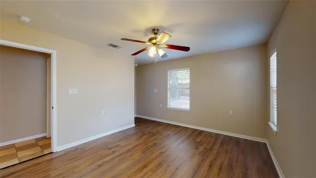 a view of an empty room with window and wooden floor